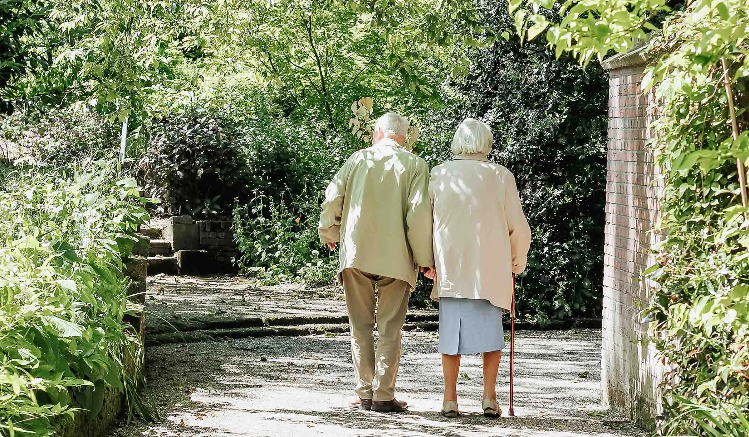 casal sénior caminhando de mãos dadas em jardim