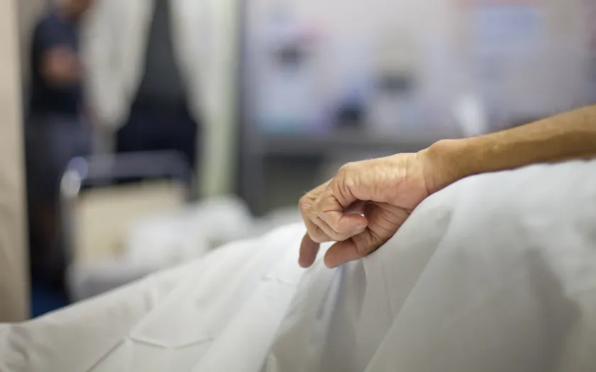 Imagem da mão de uma pessoa idosa numa cama de hospital