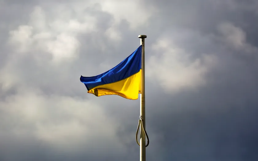 Imagem da bandeira Ucrâniana sob um céu com núvens de tempestade