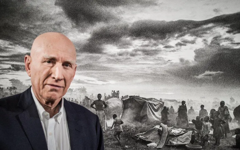 Imagem de Sebastião Salgado junto a uma das suas fotografias sobre refugiados