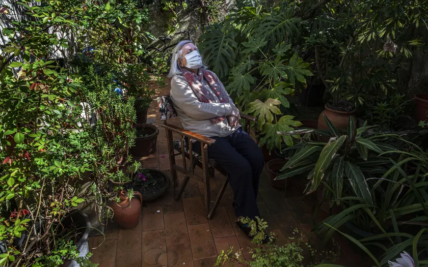 Imagem de uma mulher de máscara num canto do jardim