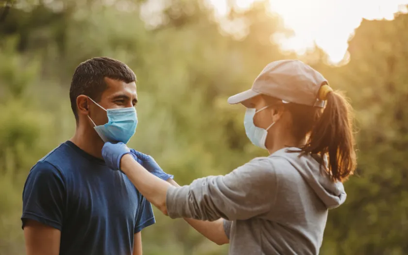 Imagem de um casal a caminhar numa floresta com uma másca de proteção