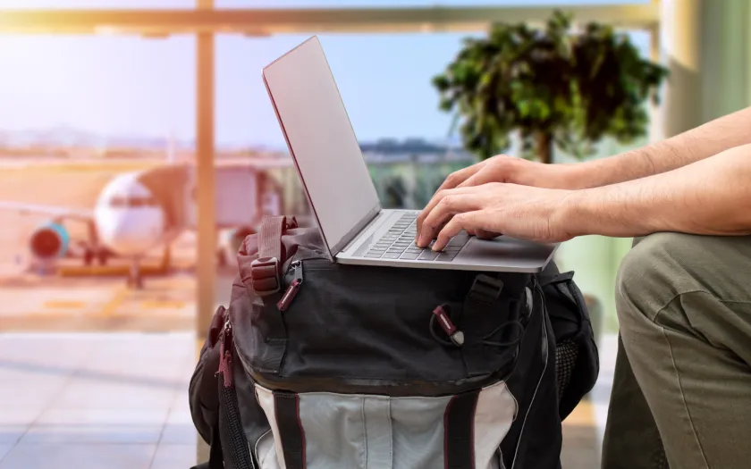 Imagem de uma pessoa a trabalhar no computador, no aeroporto, para ilustrar o artigo sobre nómadas digitais