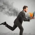 Imagem de uma homem com um computador prestes a explodir-lhe nas mãos