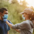 Imagem de um casal a caminhar numa floresta com uma másca de proteção