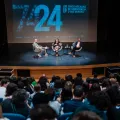 Imagem do auditório da Escola Secundária de Camões, em Lisboa, com Hugo van der Ding a moderar a conversa entre os alunos, Mónica Vieira, e o economista Pedro Freitas