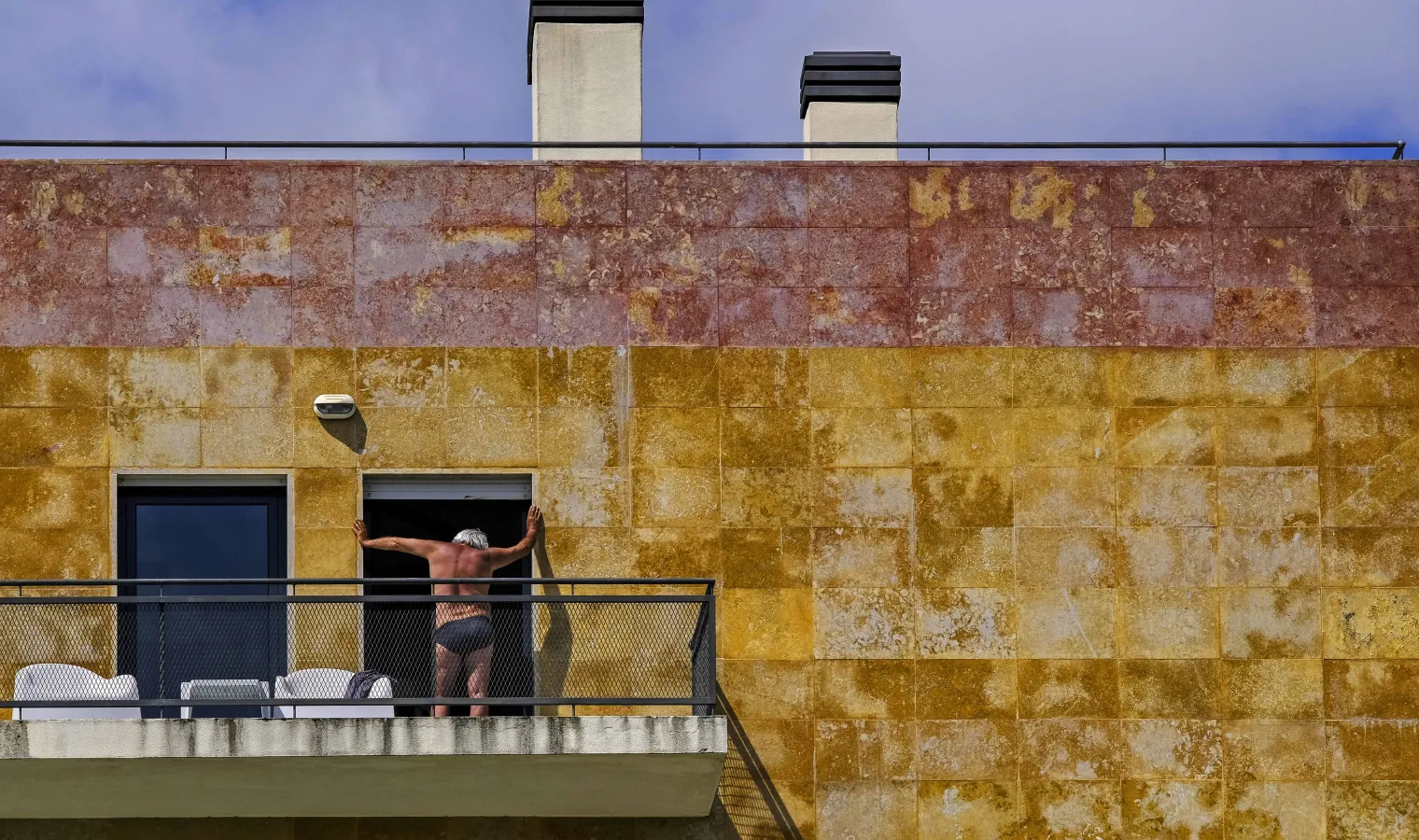 Imagem de um homem à varanda no Confinamento decretado pelo governo leva os lisboetas a ficar em casa. Parque das Nações, em Lisboa/Leonardo Negrão