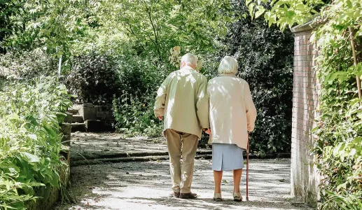 casal sénior caminhando de mãos dadas em jardim