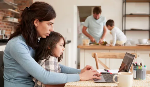 Imagem de uma mulher a trabalhar ao computador com a filha ao colo