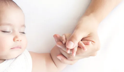 Imagem de um bebé de mão dada com a mãe