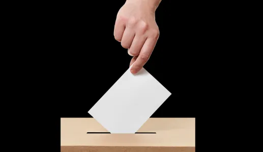 Imagem de uma mão a colocar o voto na urna eleitoral. Crédito: Canva