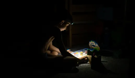 Imagem de um menino a brincar, às escuras; durante um apagão em Kiyv, na Ucrânia. Créditos: shutterstock