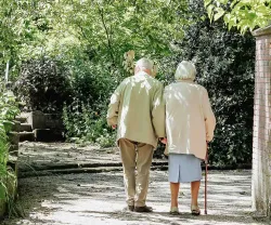 casal sénior caminhando de mãos dadas em jardim