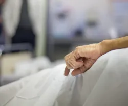 Imagem da mão de uma pessoa idosa numa cama de hospital