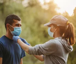 Imagem de um casal a caminhar numa floresta com uma másca de proteção
