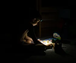 Imagem de um menino a brincar, às escuras; durante um apagão em Kiyv, na Ucrânia. Créditos: shutterstock